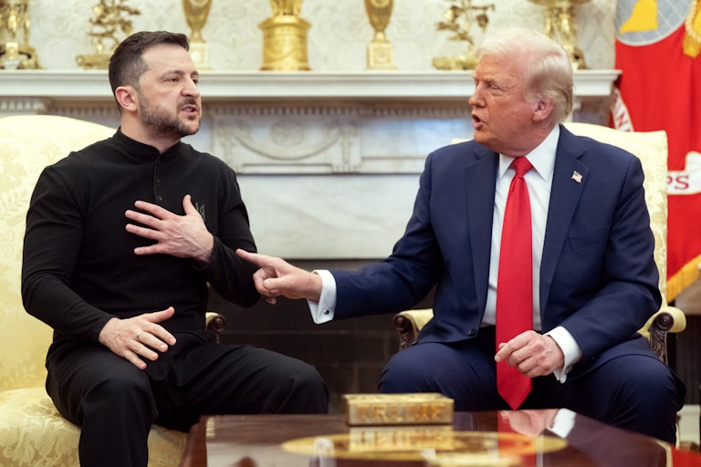 Volodymyr Zelenskiy puts his hand on his chest, while Donald Trump points at him and speaks. The two men are sitting in the Oval Office