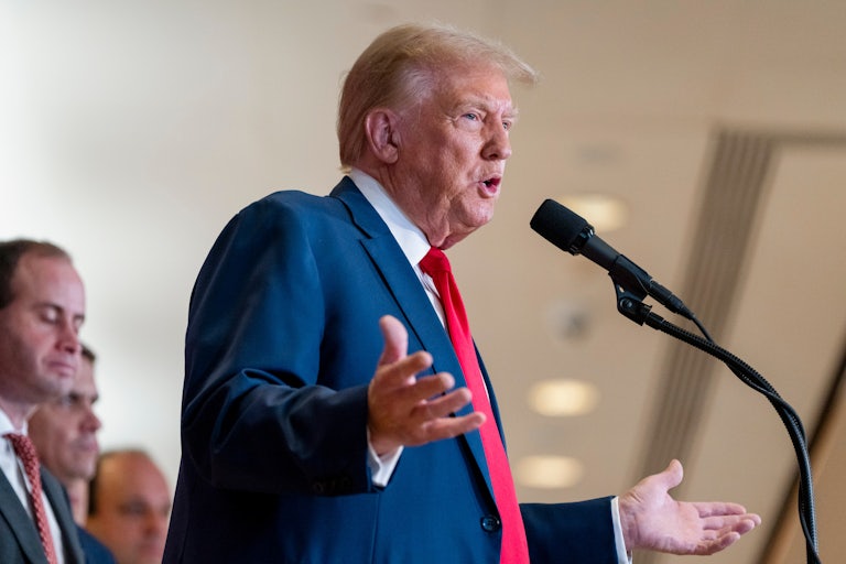 Donald Trump gestures while speaking into a microphone