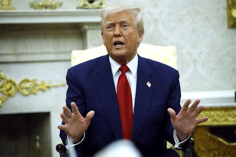 Donald Trump raises his hands defensively while speaking in the Oval Office of the White House.